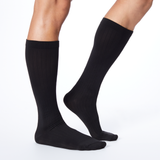Side profile of a man wearing Dr. Scholl's black knee high compression socks.