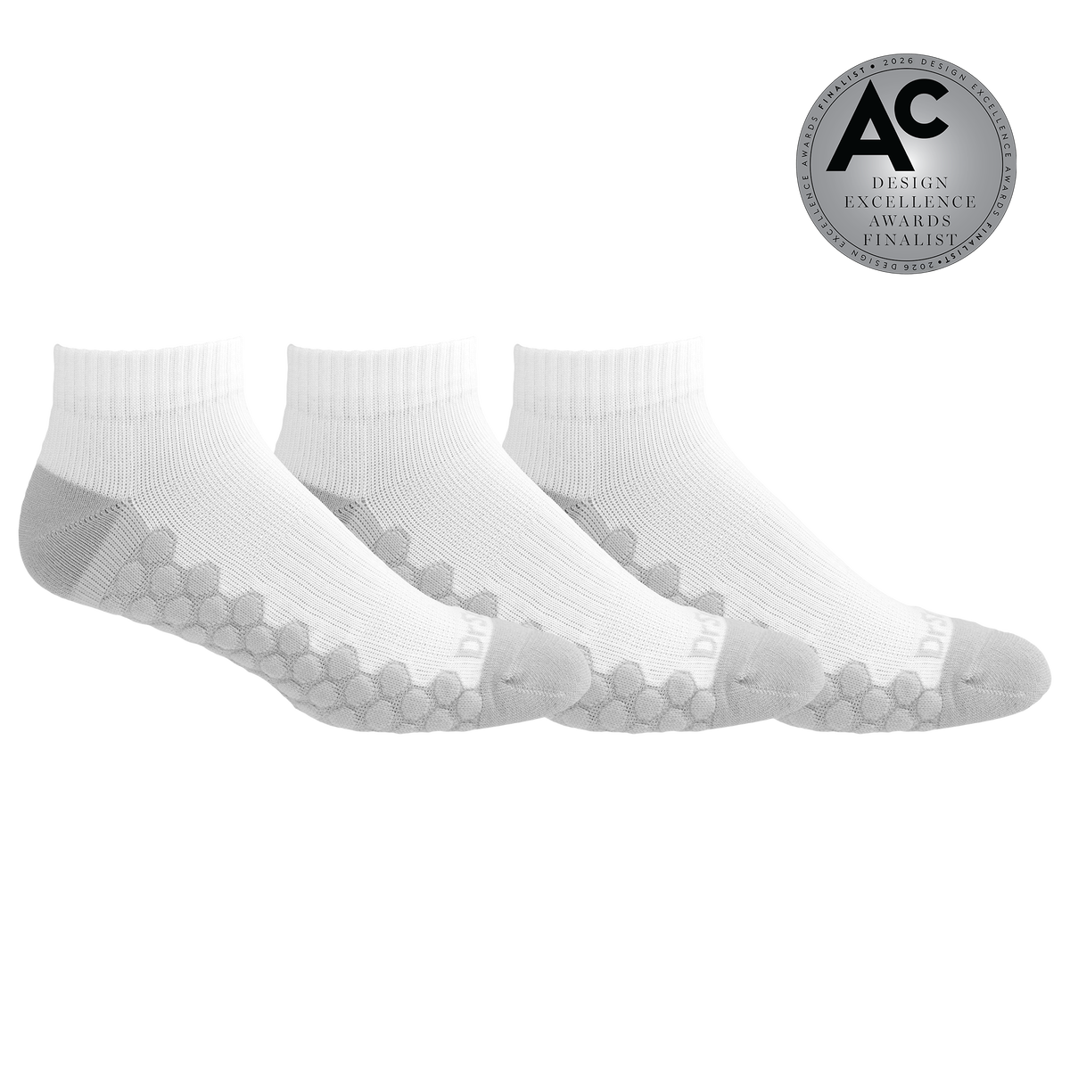 Three white ankle socks with gray grip patterns on the sole and heel, arranged in a row on a white background with a silver 'Design Excellence Awards Finalist' badge in the top right corner.