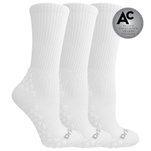 Three white ribbed crew socks with raised grip dots on the sole and heel, shown on a white background with a silver award badge reading Design Excellence Awards 2026 Design Finalist.