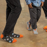 Two people wearing gray socks with colorful Halloween designs on a concrete floor.