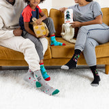 Two adults and a child sitting on a couch wearing colorful socks with various patterns. thumbnail