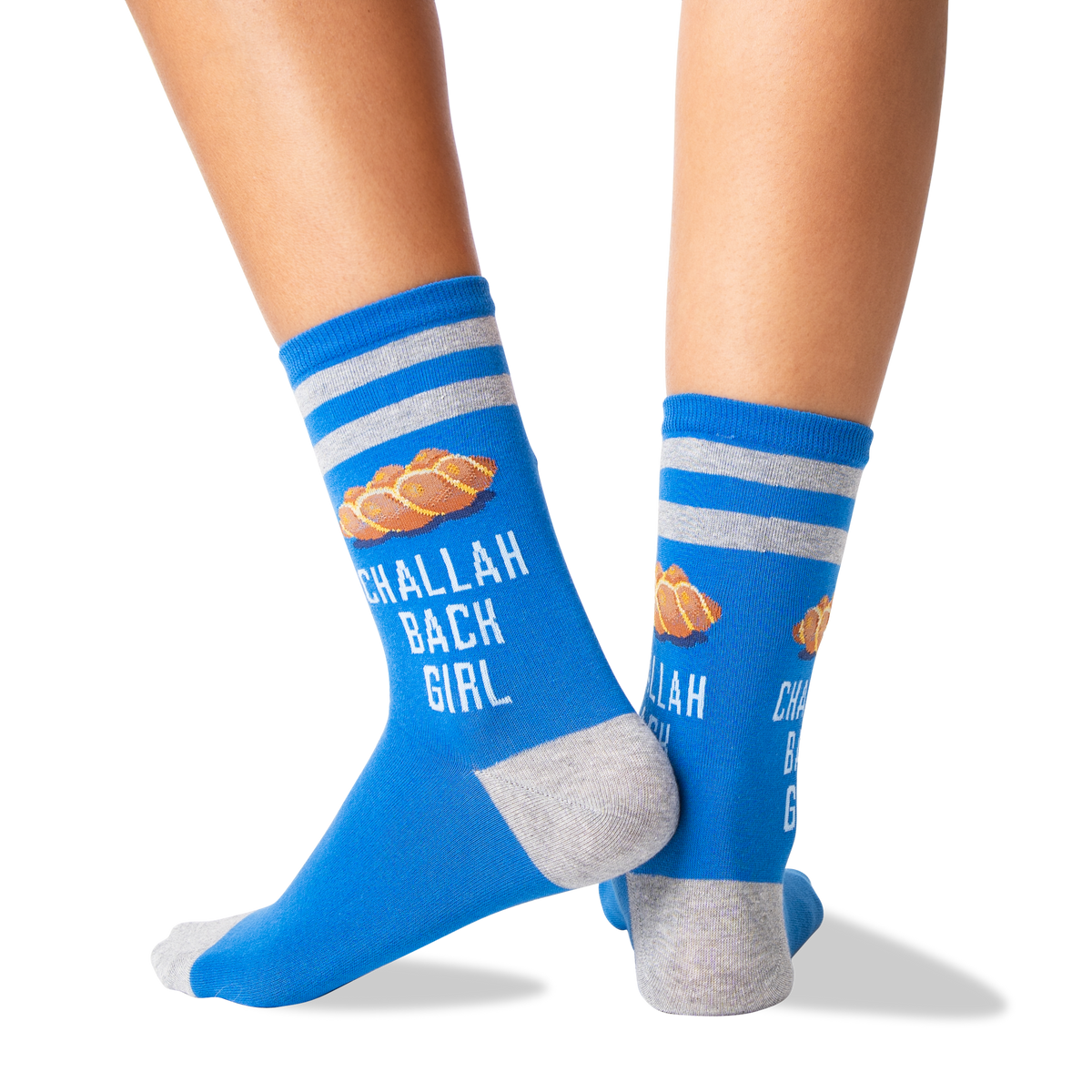 A pair of blue crew socks with gray stripes and heels/toes, featuring a croissant graphic and the text 'CHALLAH BACK GIRL' worn on a person's feet against a white background.