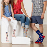 Three people sitting on a white block, wearing colorful patterned socks.