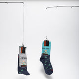 Two pairs of socks with fishing-themed designs hanging on a white background