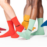 Colorful socks labeled for each day of the week worn by multiple people on a white background thumbnail