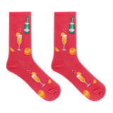 A pair of bright pink crew socks featuring a festive champagne-themed print with orange slices, champagne glasses, and a green champagne bottle, displayed against a solid white background. thumbnail