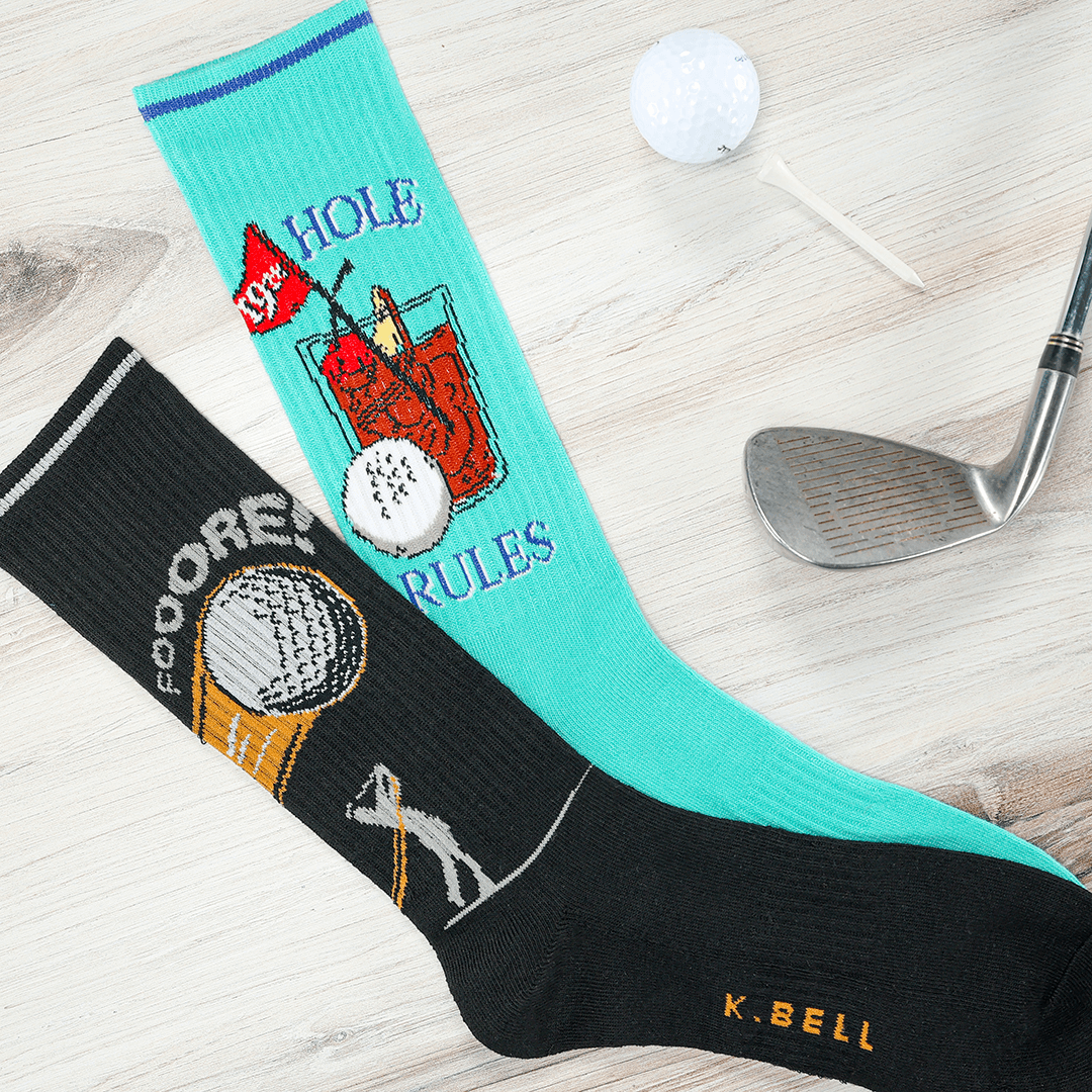Golf-themed socks with humorous design on a wooden surface with golf club and ball.