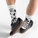 White socks with black palm tree design worn with black shoes on a white background