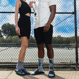 Two people standing on a tennis court wearing socks with blue and black patterns.