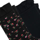 Two black socks arranged diagonally on a white background, with two featuring a small pink and red floral pattern with green leaves and one solid black sock. thumbnail
