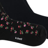 Black crew socks with a small pink and red floral pattern and green leaves, featuring the white text 'k.bell' near the toe, shown on a white background. thumbnail