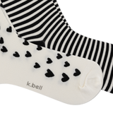 Two pairs of socks from k.bell, one in black and white stripes and the other in off-white with black hearts, shown on a white background. thumbnail