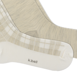 A close-up of a pair of K.Bell socks in a soft beige and white colorway.