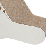 Two pairs of crew socks arranged diagonally on a white background, showing different colorways: one heathered tan pair and one white pair with a small brown and light blue argyle pattern.