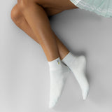 Person wearing light blue socks with a small embroidered golf ball on a light gray background