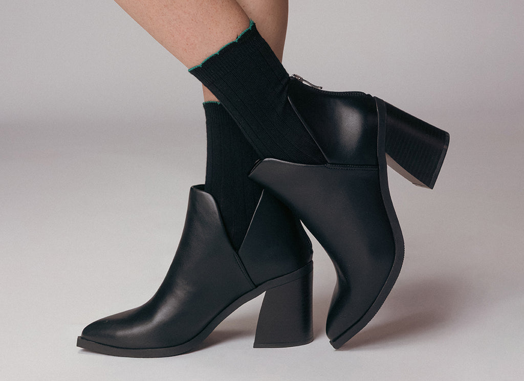 Black ankle boots with block heels on a neutral background