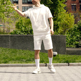 Person wearing a white outfit standing outdoors with greenery in the background