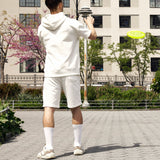 Person in white outfit playing with a yellow frisbee in an urban park setting