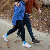 Two people walking together on a path with autumn leaves around