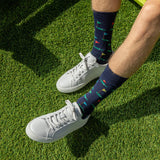 White sneakers with colorful golf-patterned socks on a grassy surface thumbnail
