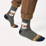 Gray socks with a whiskey glass graphic and text that says "Whiskey Helps"  worn with brown pants on a white background thumbnail