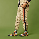 Person wearing checkered pants with side stripes and colorful socks on a green background thumbnail