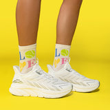 White sneakers and socks with colorful letters on a yellow background