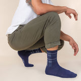Person wearing green pants and blue plaid socks on a beige background thumbnail