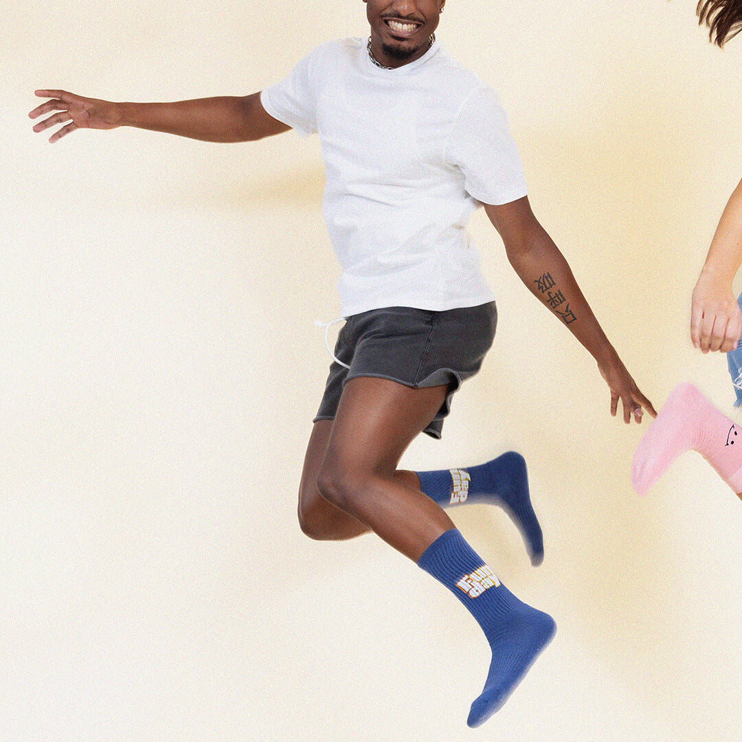 Person wearing blue socks with a design that says "Sun day Fun day" on a beige background