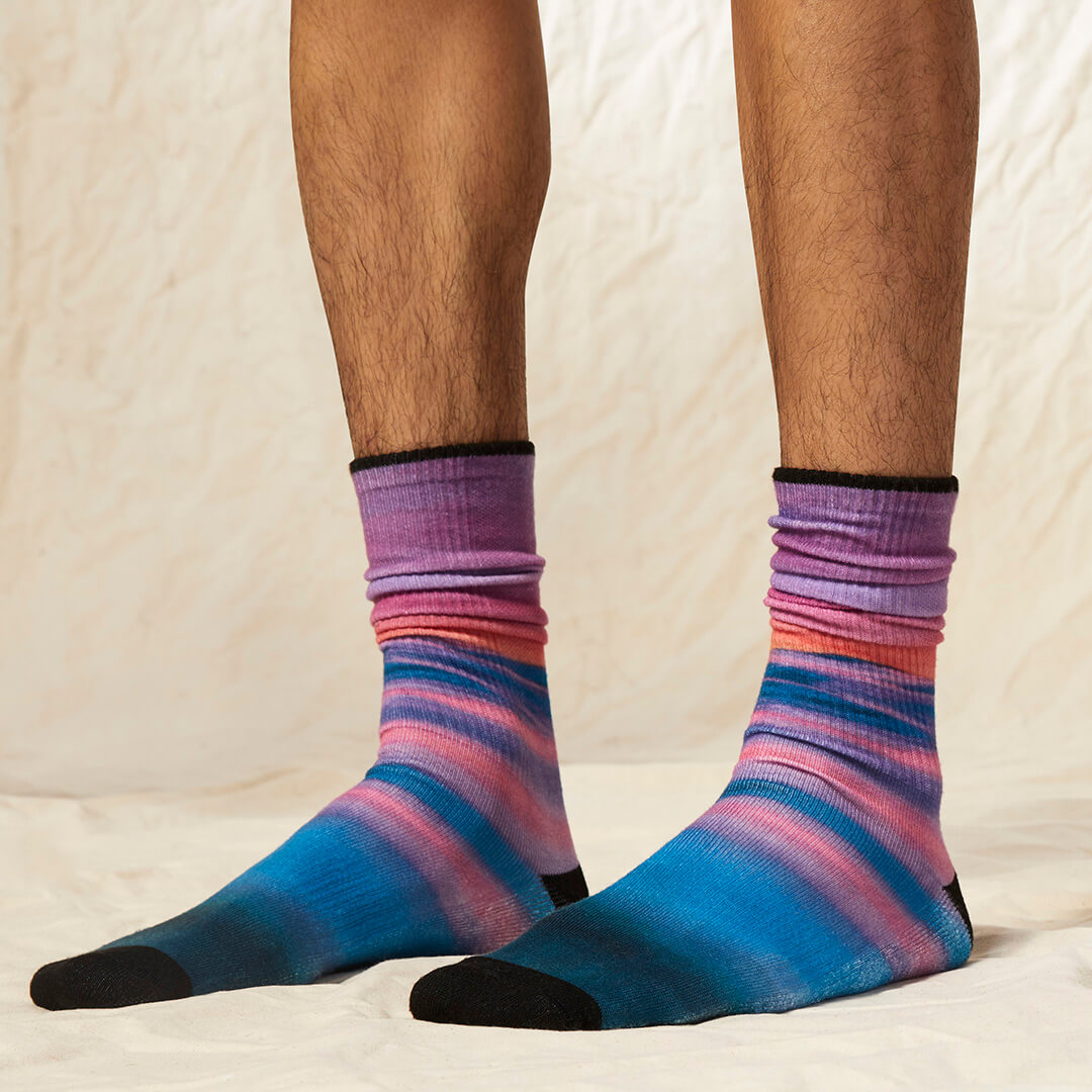Colorful striped socks worn by a person on a neutral background