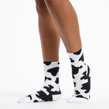 Cow print socks worn by a person on a white background thumbnail
