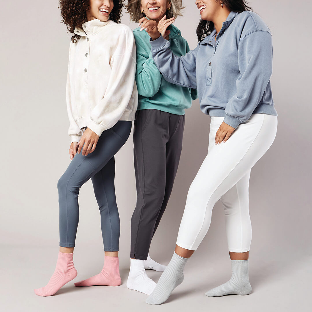 Three women wearing colorful outfits with leggings against a plain background