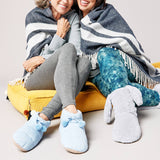 Two people sitting together wrapped in a blanket, wearing cozy slippers. thumbnail