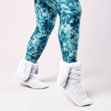 Blue tie-dye leggings with white fuzzy socks on a light pink background