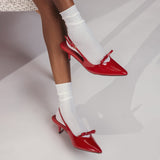 Red high-heeled shoes worn with white socks on a neutral background