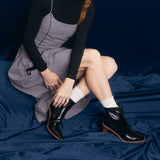 Person wearing a checkered dress and black boots with white socks sitting on a blue velvet background thumbnail