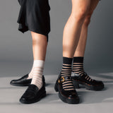 Two pairs of legs wearing black shoes and striped socks on a gray background thumbnail